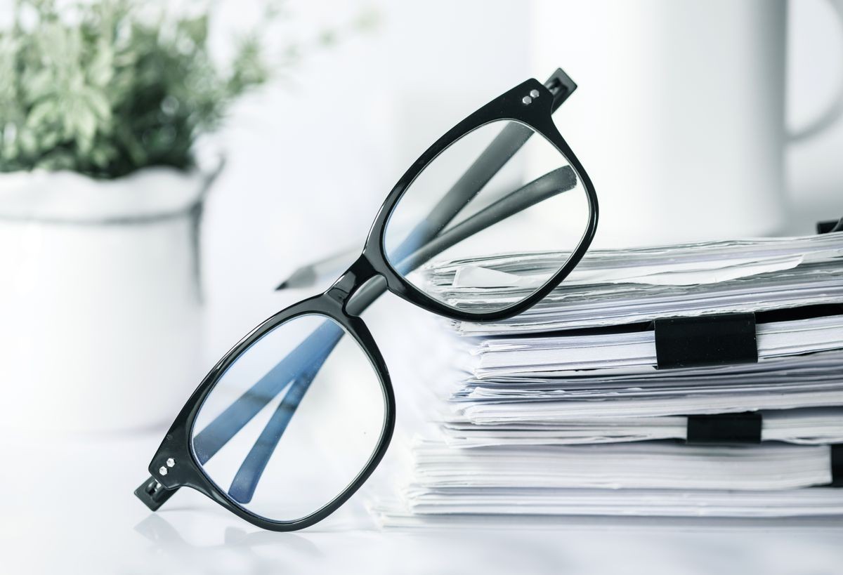 Close up a black reading eyeglasses on stacking of office paper , business working document and information data concept.